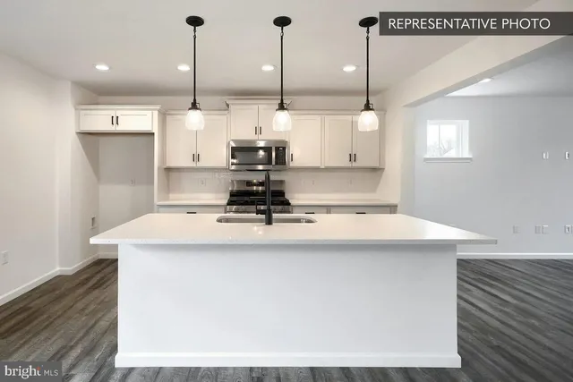 a kitchen with kitchen island a sink a stove a refrigerator and white cabinets with wooden floor