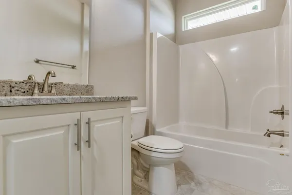 a bathroom with a granite countertop toilet sink and mirror