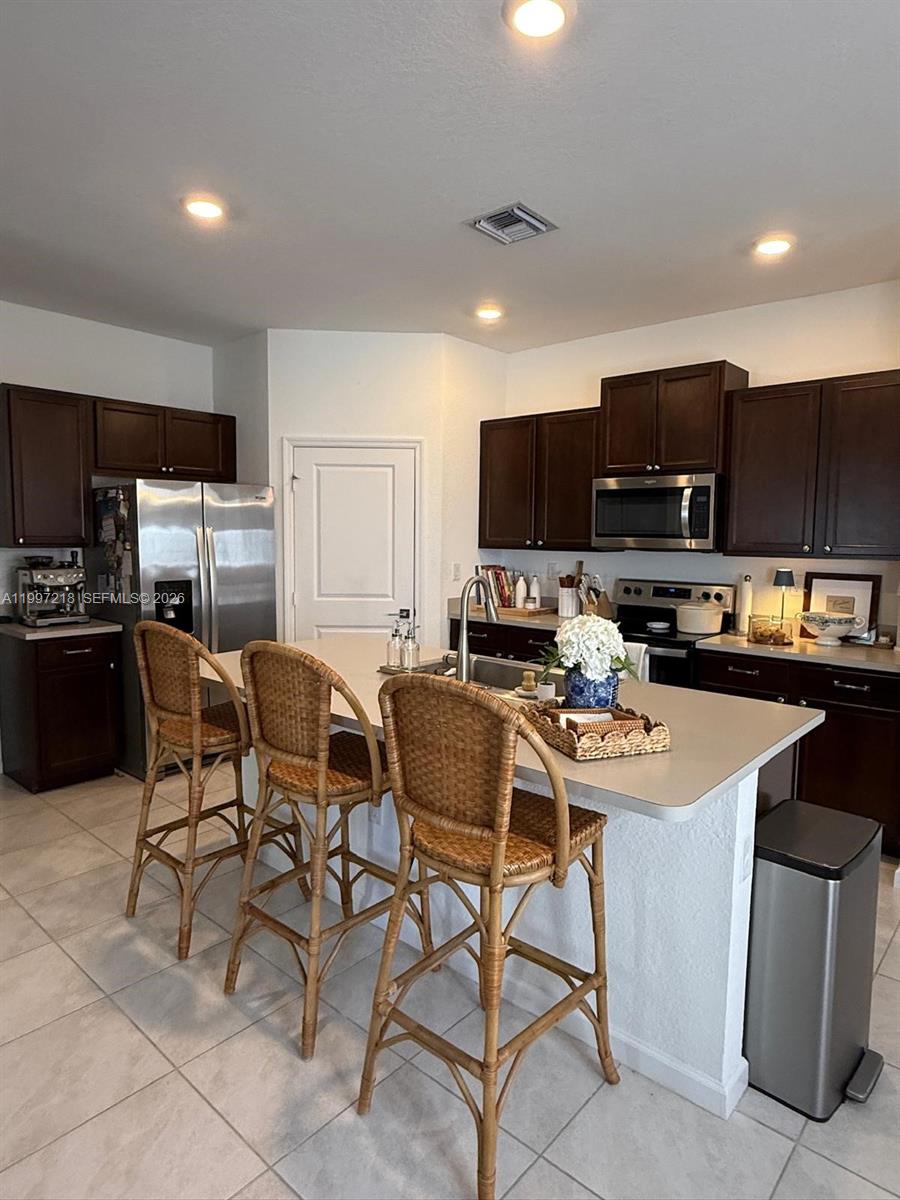 13233 Southwest 272nd Street Homestead, FL 33032 - Photo 9 of 21 a kitchen with stainless steel appliances a stove a sink a microwave a refrigerator and chairs