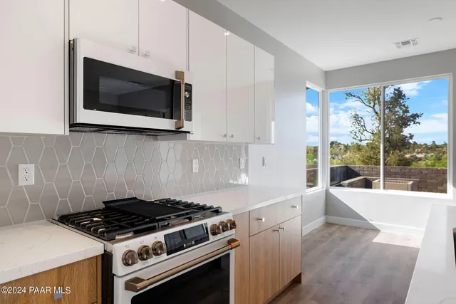 a kitchen with stainless steel appliances a stove a microwave and white cabinets