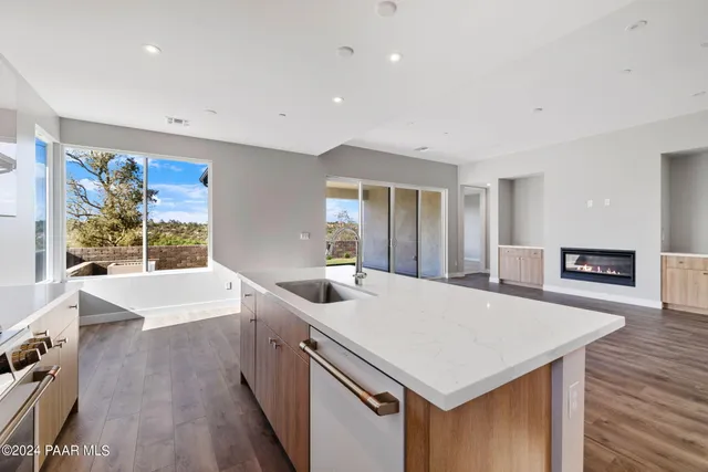 a view of kitchen island with stainless steel appliances wooden floor dining table and chairs