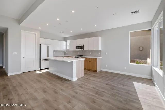 a view of kitchen with kitchen island granite countertop stainless steel appliances refrigerator sink and cabinets