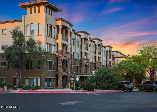 a front view of a building with lot of cars and trees