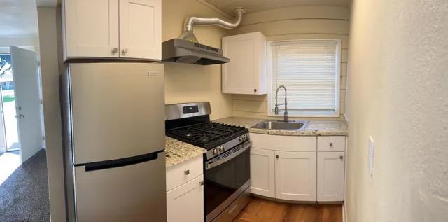 a kitchen with stainless steel appliances granite countertop white cabinets and a stove
