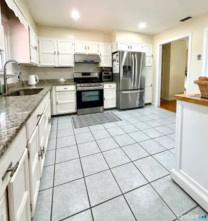a kitchen with stainless steel appliances granite countertop a refrigerator and a stove top oven
