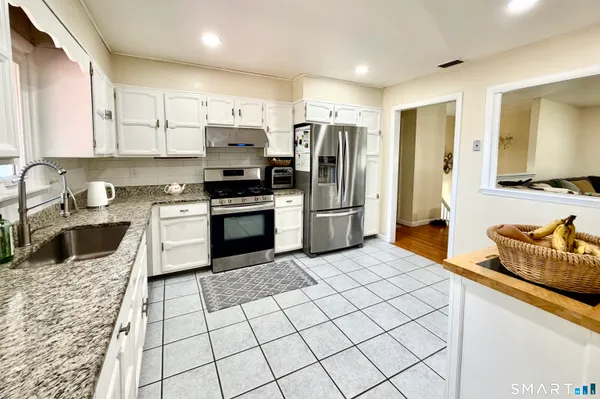 a kitchen with stainless steel appliances granite countertop a stove a sink and a refrigerator