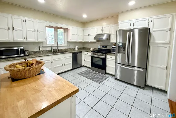 a kitchen with stainless steel appliances granite countertop a stove a sink dishwasher a refrigerator and cabinets with wooden floor