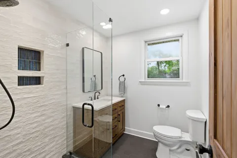 a bathroom with a granite countertop toilet sink and mirror