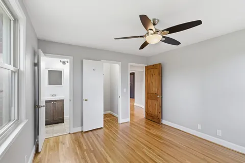 a view of empty room with wooden floor and ceiling fan