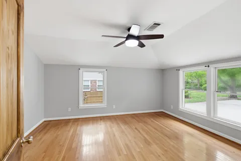 a view of empty room with wooden floor and fan