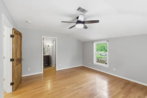 a view of empty room with wooden floor and window