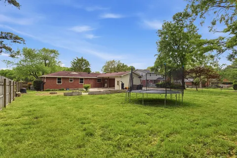 a view of a house with a big yard plants and large trees