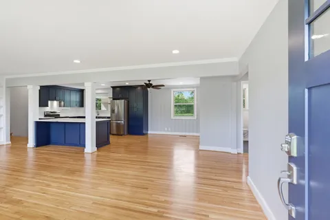 a view of kitchen with kitchen island a sink wooden floor and a refrigerator