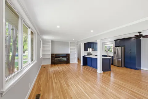 a large open kitchen with stainless steel appliances kitchen island granite countertop a refrigerator a stove a sink dishwasher with a dining table and chairs with wooden floor