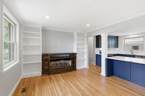 a living room with stainless steel appliances wooden floors and fireplace