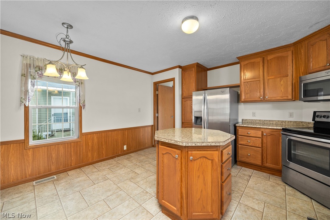 35157 Center Ridge Road, Unit 92 North Ridgeville, OH 44039 - Photo 10 of 40 Kitchen featuring a hexagonal island, wood cabinetry, stainless steel appliances, tile flooring, and a dining area with a chandelier