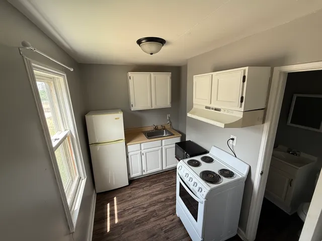 a kitchen with sink a refrigerator and white cabinets