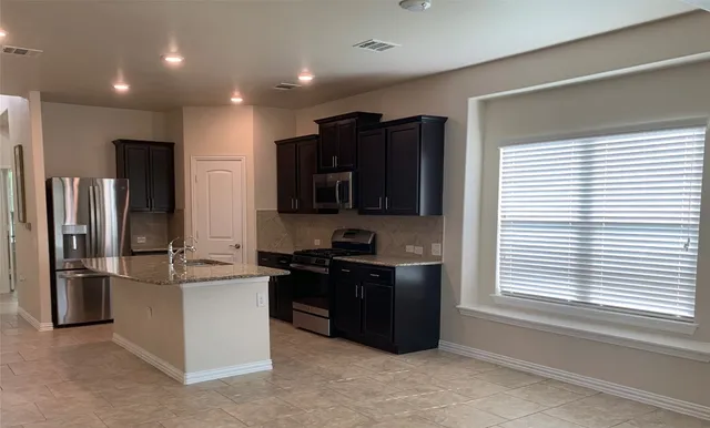 a kitchen with stainless steel appliances granite countertop a refrigerator and a stove top oven