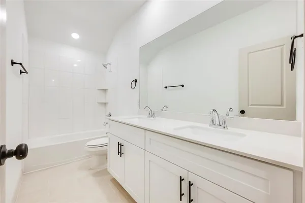a bathroom with a double vanity sink toilet mirror and bathtub