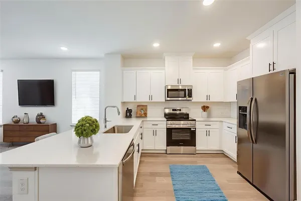 a kitchen with stainless steel appliances a stove a sink a refrigerator and a refrigerator