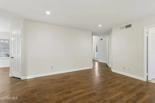 a view of an empty room with wooden floor and a window