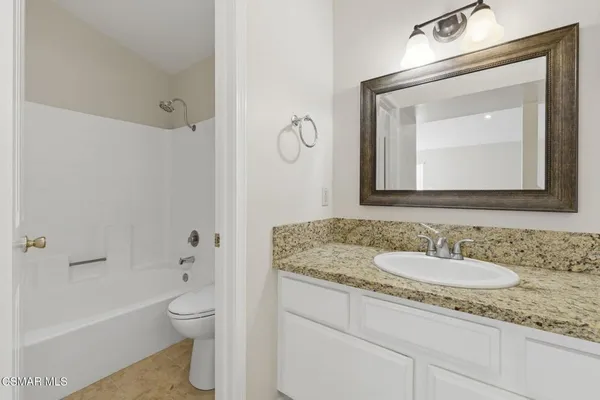 a bathroom with a granite countertop toilet a sink and a mirror