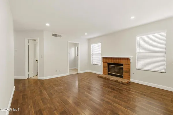 a view of empty room with wooden floor and fireplace