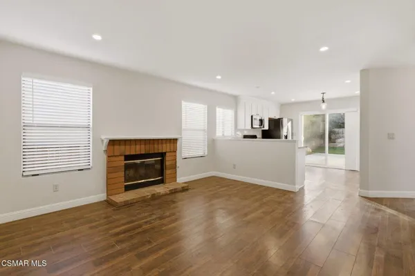 a view of a livingroom with a fireplace wooden floor and windows