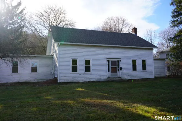 a brick house with a yard potted plants and large tree