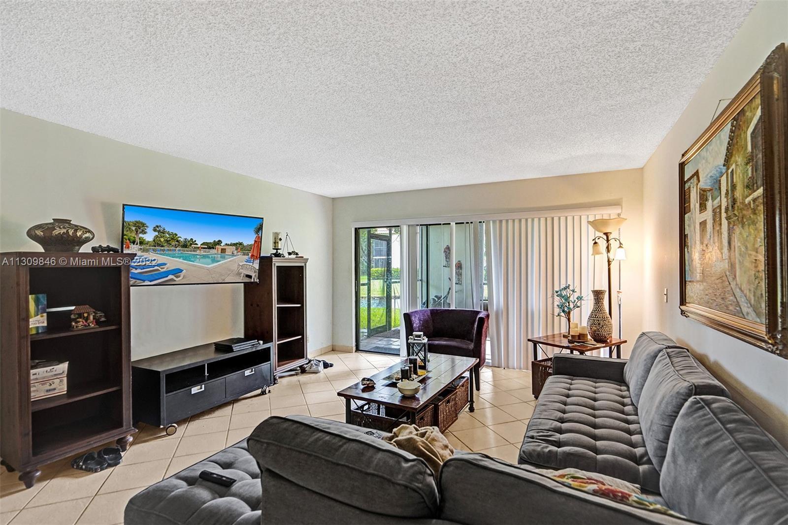 491 Racquet Club Road, Unit 101 Weston, FL 33326 - Photo 2 of 32 a living room with furniture and a flat screen tv