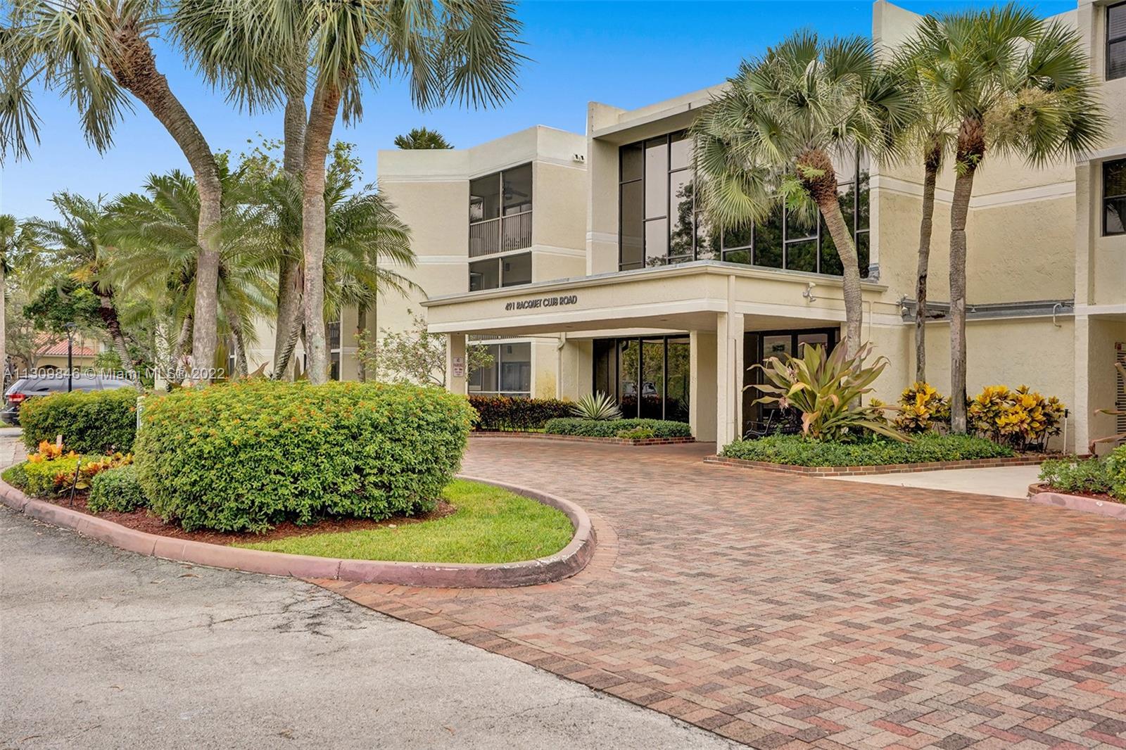 491 Racquet Club Road, Unit 101 Weston, FL 33326 - Photo 4 of 32 a view of a white house with a yard and palm trees