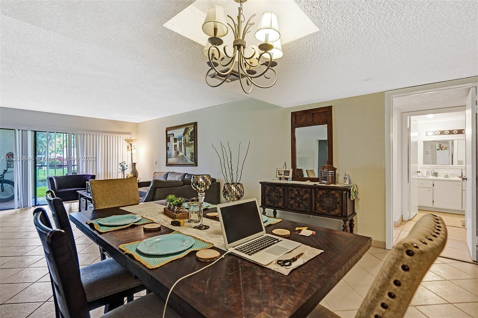 491 Racquet Club Road, Unit 101 Weston, FL 33326 - Photo 5 of 32 a living room with furniture a chandelier and a table