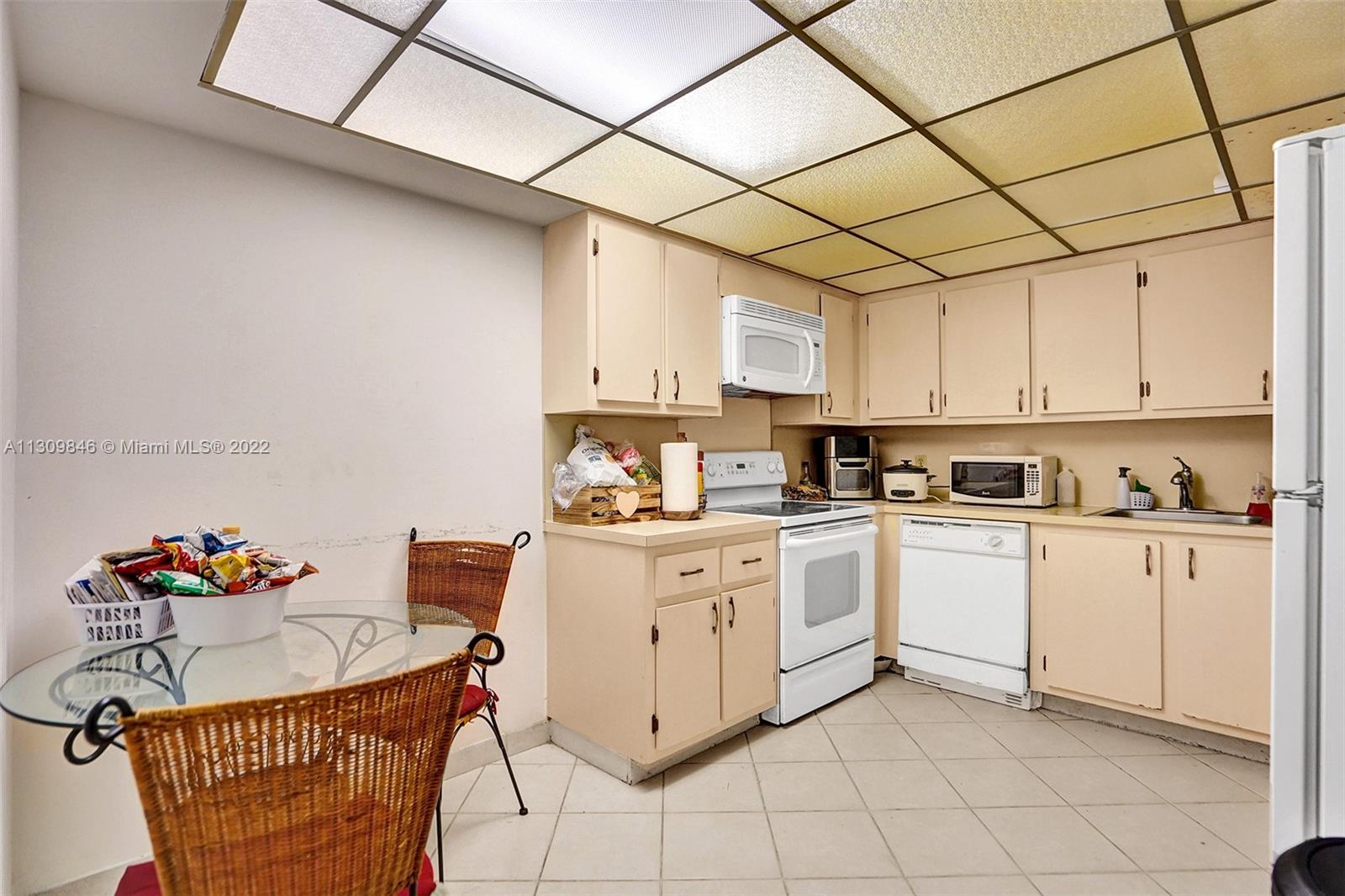 491 Racquet Club Road, Unit 101 Weston, FL 33326 - Photo 7 of 32 a kitchen with stainless steel appliances granite countertop a sink a stove a refrigerator a microwave oven with white cabinets and wooden floor
