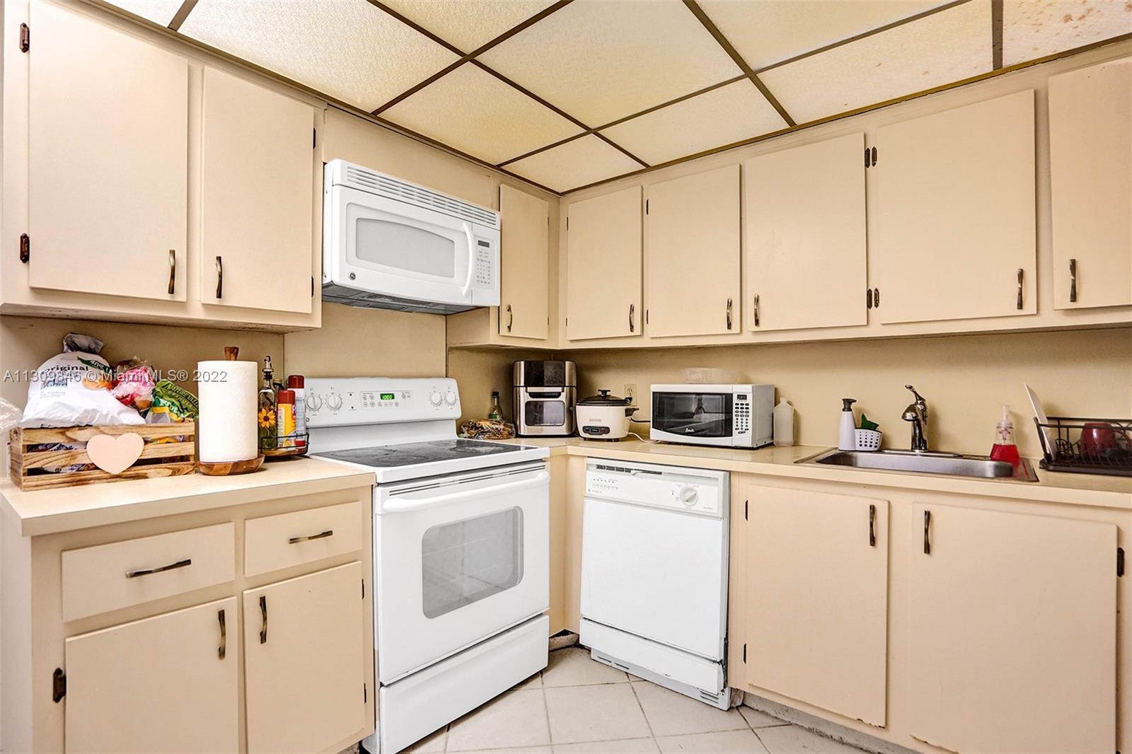 491 Racquet Club Road, Unit 101 Weston, FL 33326 - Photo 8 of 32 a kitchen with white cabinets and white appliances