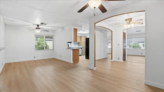 a view of an empty room with a window and wooden floor