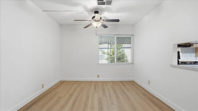 an empty room with a window and a chandelier fan