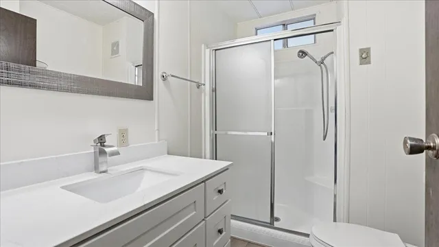 a bathroom with a shower sink vanity mirror and toilet