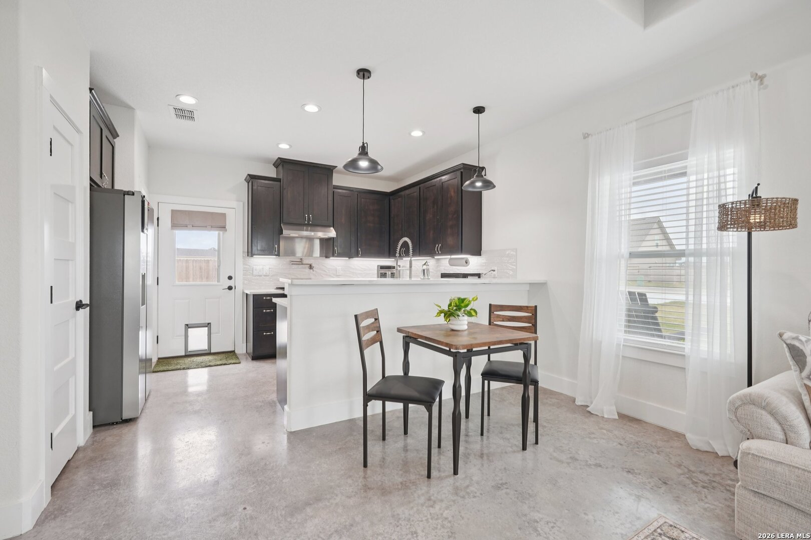 218 Colonial Lane La Vernia, TX 78121 - Photo 15 of 46 a kitchen with stainless steel appliances kitchen island granite countertop a refrigerator a sink a stove a dining table and chairs