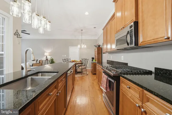 a kitchen with stainless steel appliances granite countertop a sink a stove and a wooden floor