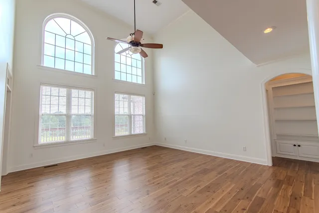 an empty room with wooden floor closet and windows