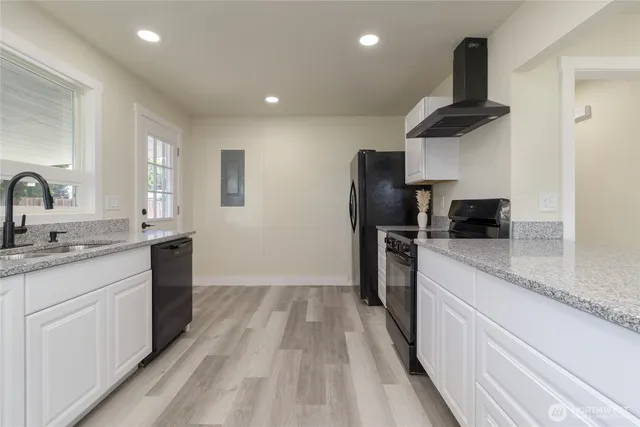 a kitchen with a sink dishwasher a refrigerator and a stove with wooden floor
