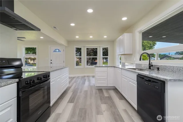 a large kitchen with stainless steel appliances granite countertop a lot of counter space and a sink