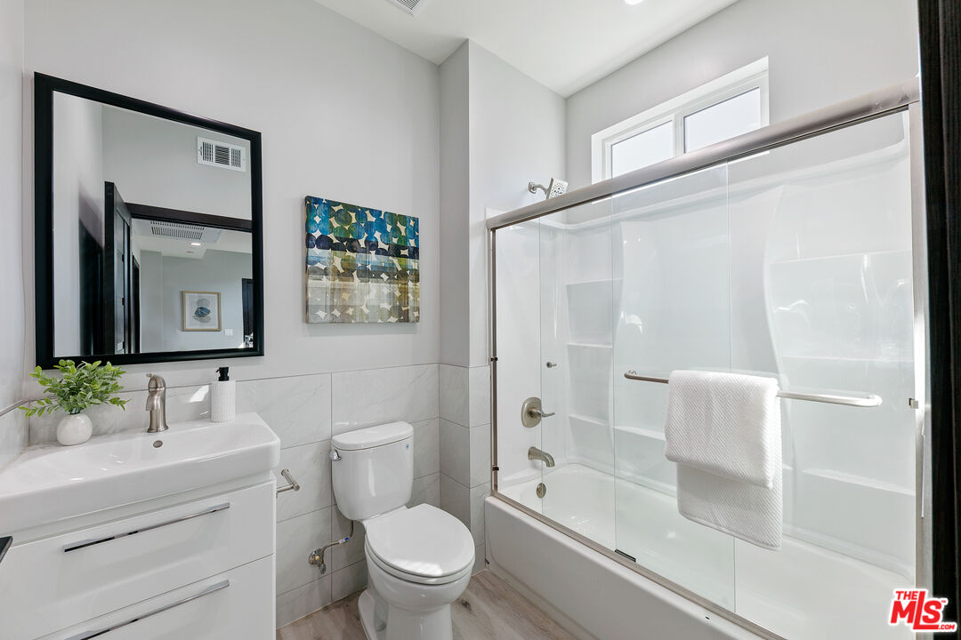 15106 Roxford Street, Unit 13621 Los Angeles, CA 91342 - Photo 16 of 22 a bathroom with a granite countertop sink a toilet and shower