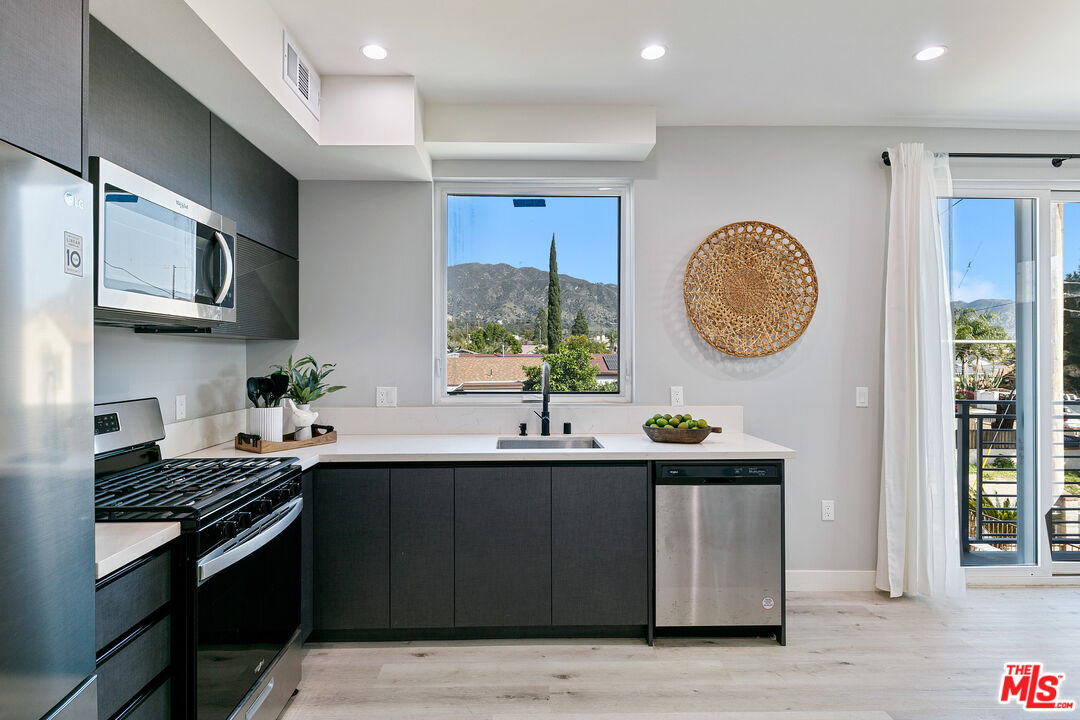 15106 Roxford Street, Unit 13621 Los Angeles, CA 91342 - Photo 19 of 22 a kitchen with stainless steel appliances granite countertop a sink a stove a oven a counter space and cabinets