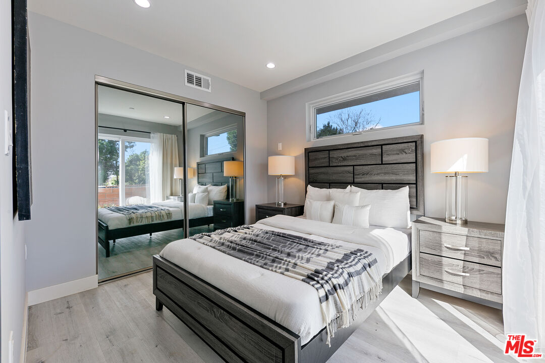 15106 Roxford Street, Unit 13621 Los Angeles, CA 91342 - Photo 22 of 22 a bedroom with a bed and a large mirror on the dresser