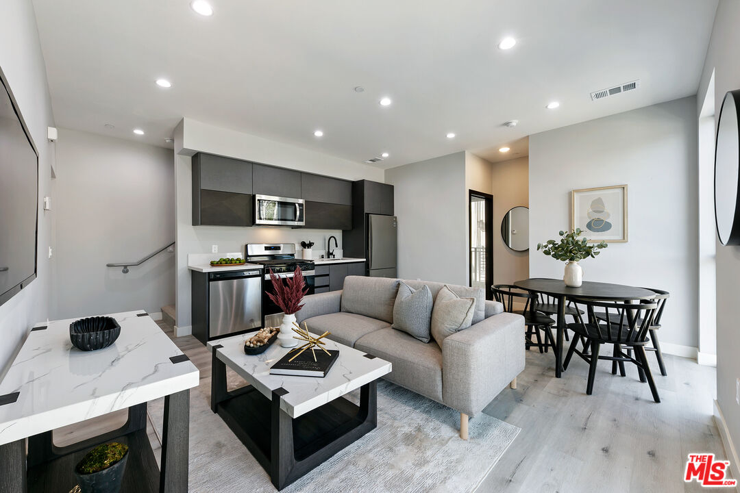 15106 Roxford Street, Unit 13621 Los Angeles, CA 91342 - Photo 7 of 22 a living room with stainless steel appliances kitchen island a table and a refrigerator