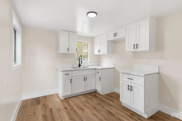a view of an empty room with wooden floor and windows