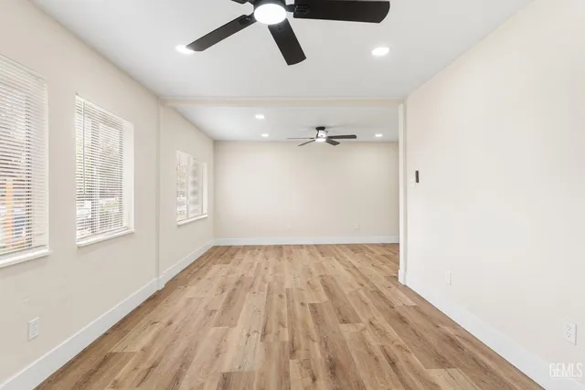 an empty room with wooden floor cabinet and windows