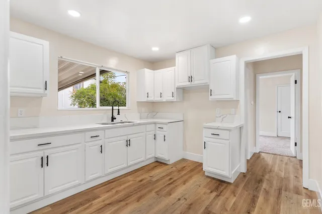 a kitchen with white cabinets and wooden floors
