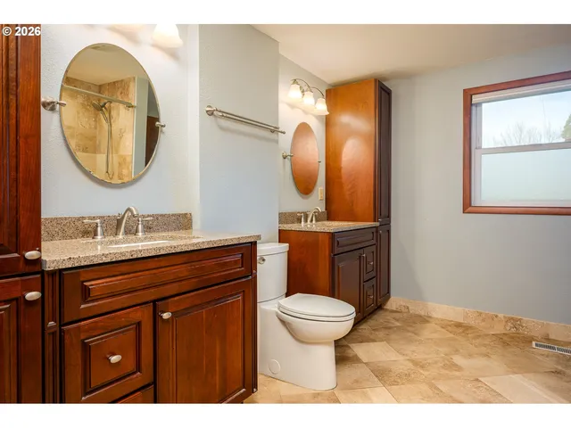 a bathroom with a toilet a sink a mirror and a window